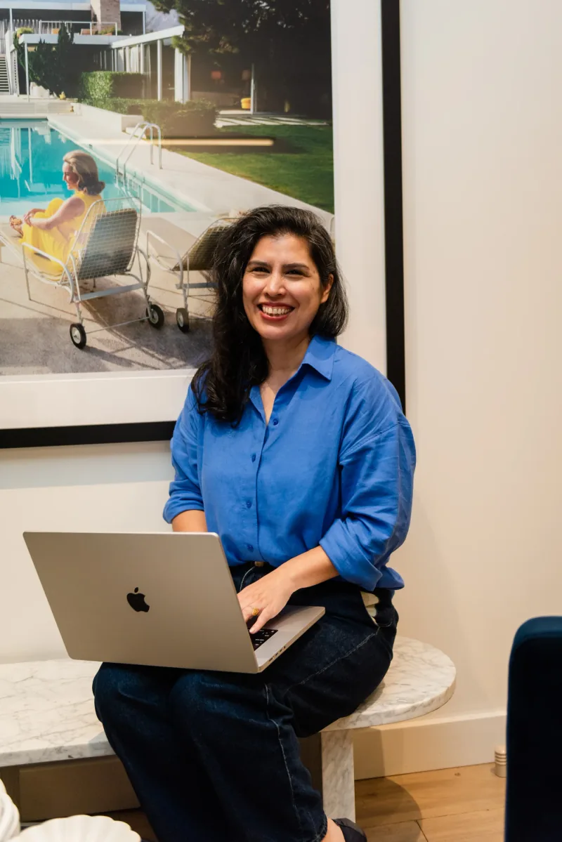 Jane smiling with a laptop, seated in the studio.